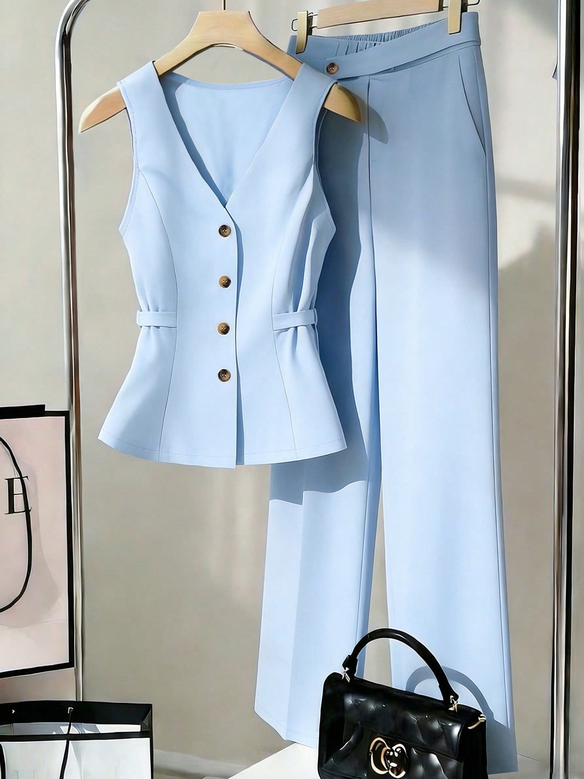 Open sleeveless button-front vest top and wide-leg pants set in light blue, laid out on a hanger