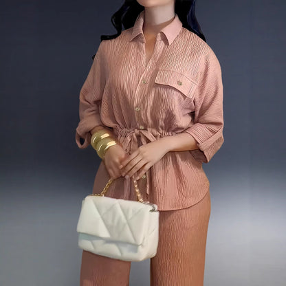 Dusty rose belted shirt with lapel collar and a white quilted handbag, close-up
