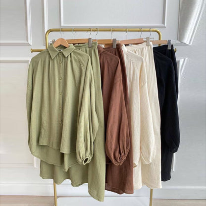 Loose-fitting shirt and skirt sets in olive green, brown, ivory and black hanging on a clothing rail